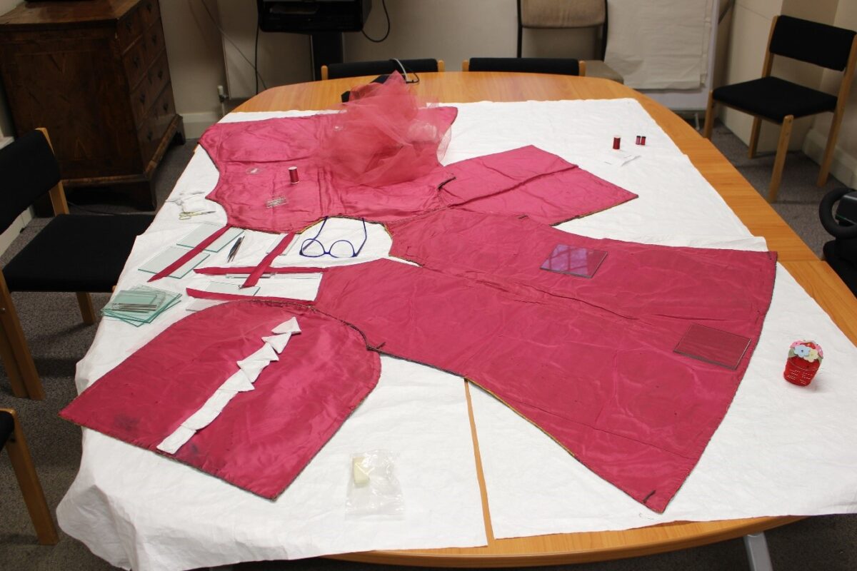 The bright raspberry pink silk taffeta lining of the tabard.
