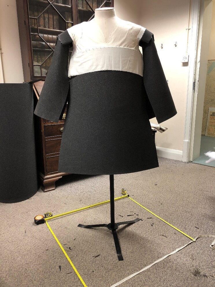 The mannequin for the tabard with the dimensions of the display case marked out on the floor.
