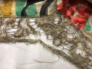 Image shows the fragile metallic thread lace being stitch supported onto fine Nylon net