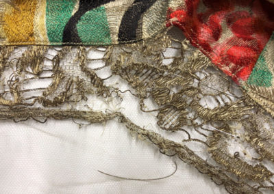 Image shows the fragile metallic thread lace being stitch supported onto fine Nylon net