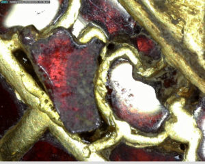 Individual garnet being repositioned in gold cell